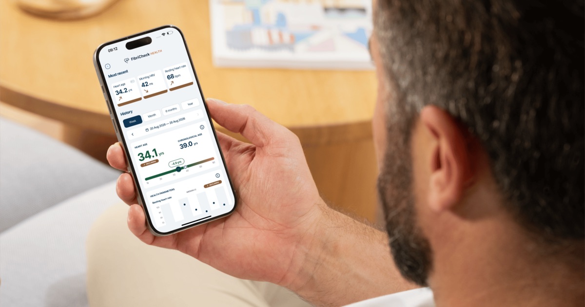 Iemand bekijkt het FibriCheck Health-scherm op de telefoon, met een hartleeftijd van 34,1 jaar naast een chronologische leeftijd van 39,0 jaar, een ochtend-HRV van 42 ms en een hartslag in rust van 68 bpm.