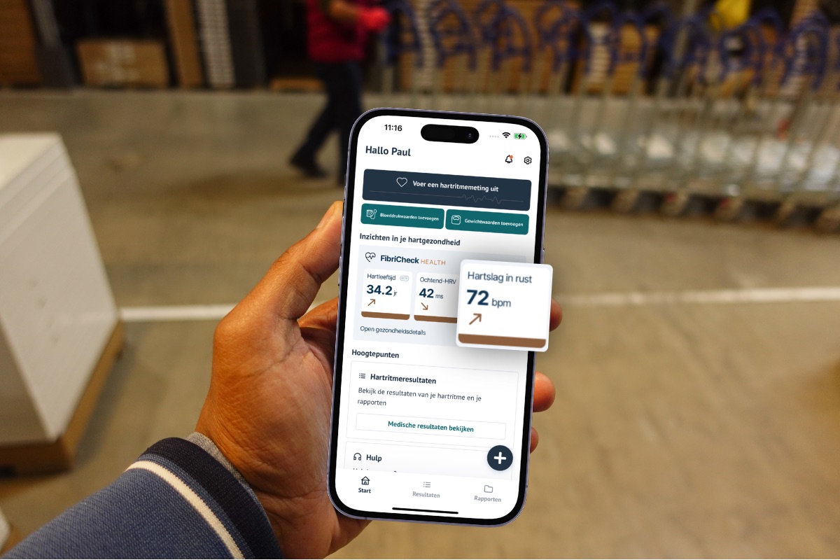Iemand houdt een telefoon vast met het startscherm van de FibriCheck-app open, met een hartslag in rust van 72 bpm naast de inzichten hartleeftijd en ochtend-HRV.